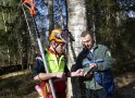 zwei Männer stehen vor einem Baum mit weißer Rinde und schauen gemeinsam einen kleinen Zweig an