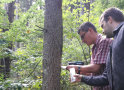 Zwei Personen nehmen mit Hilfe einer Bohrmaschine Spanproben von einem Baumstamm