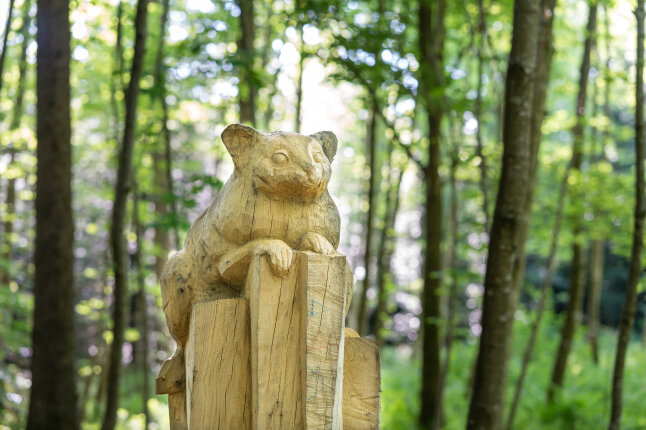 Geschnitzte Figur auf einem Holzstamm im Osinger Wald